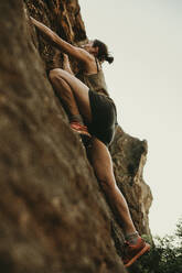 Entschlossene Frau klettert auf einen Felsen im Wald - DMGF00127