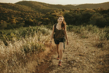 Adventurous woman walking in forest during sunset - DMGF00132