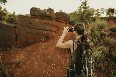 Weiblicher Wanderer, der ein Foto mit seinem Smartphone macht, während er im Wald steht - DMGF00134