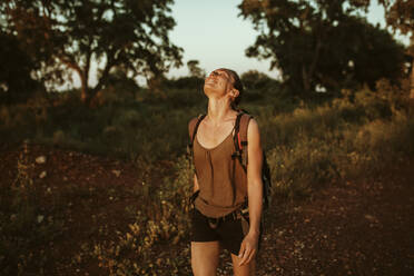 Lächelnde Frau mit zurückgelegtem Kopf beim Wandern im Wald - DMGF00135