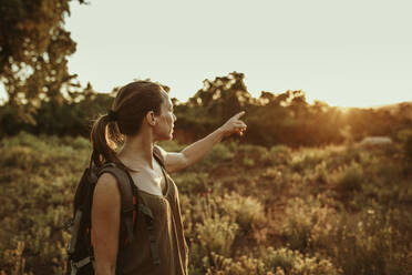 Wanderin, die auf den Sonnenuntergang im Wald zeigt - DMGF00139