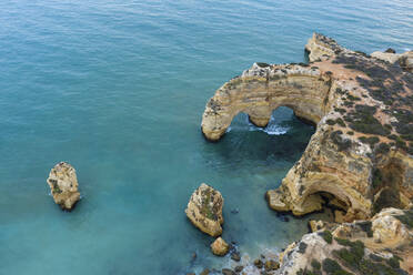 Portugal, Algarve, Lagoa, Drone view of turquoise waters of Atlantic Ocean and coastal rock arch - RUEF03066