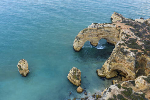 Portugal, Algarve, Lagoa, Drohnenblick auf das türkisfarbene Wasser des Atlantiks und den Felsbogen an der Küste - RUEF03066