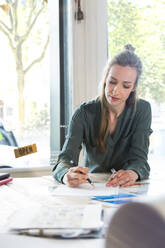 Woman working at desk in office - FKF03833