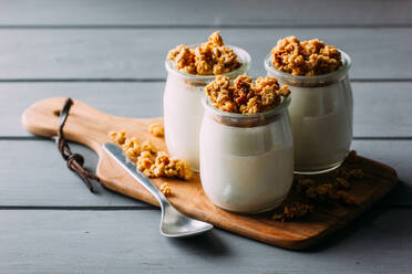 Glass bottles with cold tasty milk and natural delicious walnuts with spoon on wooden tray - ADSF14213