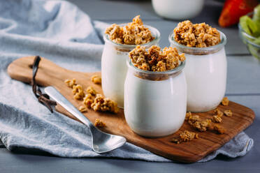 Glasflaschen mit kalter leckerer Milch und natürlichen leckeren Walnüssen mit Löffel auf Holztablett mit Früchten - ADSF14215