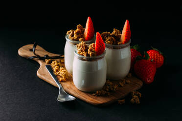 Glasflaschen mit kalter schmackhafter Milch und natürlichen leckeren Walnüssen mit Löffel auf Holztablett und Erdbeeren oben drauf - ADSF14216