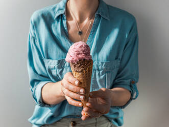 Hand holding ice cream in cone. Ice cream scoop in cone in woman hands - ADSF14222