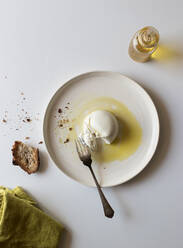 Plate with delicious fresh burrata placed on white tabletop near piece of bread and oil with salt - ADSF14241