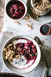 Leckere Frühstücksschüssel mit Quinoa, Reis und Grütze neben Teetasse und Zeitung - ADSF14275