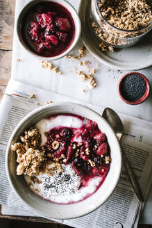 Leckere Frühstücksschüssel mit Quinoa, Reis und Grütze neben Teetasse und Zeitung - ADSF14275