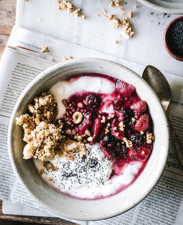 Leckere Frühstücksschüssel mit Quinoa, Reis und Grütze neben Teetasse und Zeitung - ADSF14276