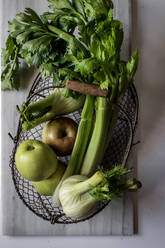 From above metal basket with apples, celery, fennel bulbs and walnuts arranged on board against white background - ADSF14306