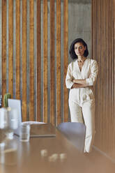 Female entrepreneur with arms crossed standing at entrance in office - MCF01252