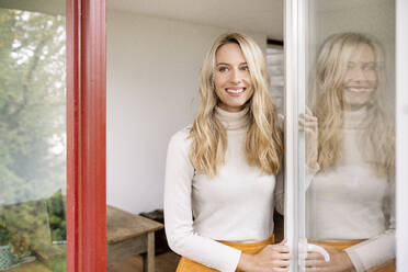 Thoughtful female entrepreneur standing by window in office - PESF02071