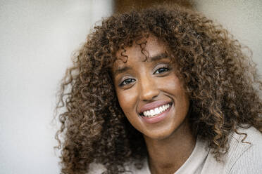 Close-up of smiling female entrepreneur with curly hair in office - PESF02077
