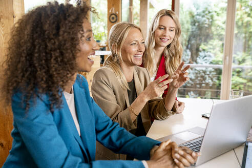 Fröhliche weibliche Mitarbeiter diskutieren über Geschäftsstrategien am Schreibtisch im Büro - PESF02094