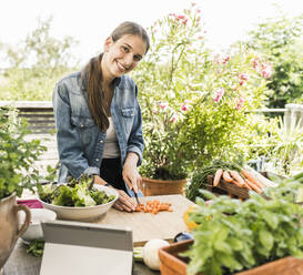 Smiling woman chopping vegetables on cutting board in yard - UUF21005