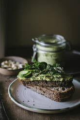 Toasts mit grüner Cashewpastete und Gurkenscheiben auf Holzbrett - ADSF14316