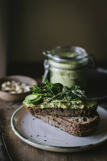 Toasts mit grüner Cashewpastete und Gurkenscheiben auf Holzbrett - ADSF14316