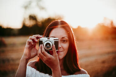 Woman using vintage camera at sunset - EBBF00678