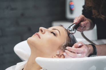 Friseurin wäscht Haare einer jungen Frau - ADSF14350