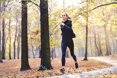 Junge Frau joggt im Herbstwald - BSZF01670