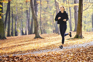 Junge Frau joggt im Herbstwald - BSZF01680