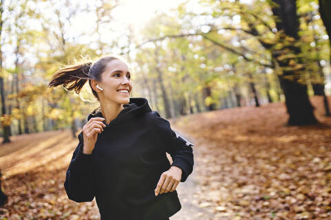 Junge Frau joggt im Herbstwald, lizenzfreies Stockfoto