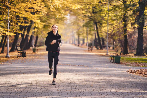 Young woman jogging in autumn forest stock photo