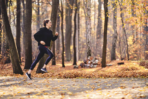 Junge Frau joggt im Herbstwald, lizenzfreies Stockfoto