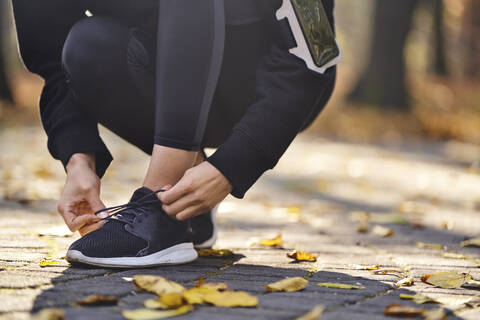 Young woman tying her running shoe stock photo