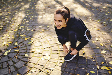 Young woman tying her running shoe - BSZF01700