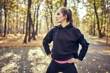 Junge Joggerin in der Pause mit Blick zur Seite im Herbstwald - BSZF01705