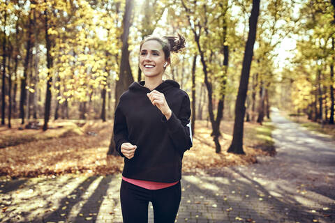 Junge Frau joggt im Herbstwald, lizenzfreies Stockfoto