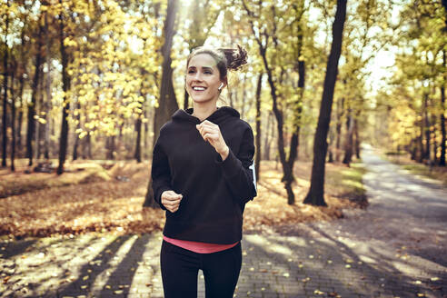 Junge Frau joggt im Herbstwald - BSZF01707