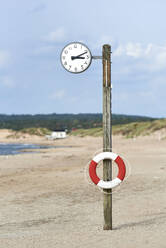 Inflatable tube on clock pole at beach against sky - JEDF00333