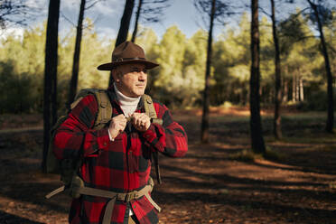 Bushcrafter wearing hat while standing in forest - SASF00033