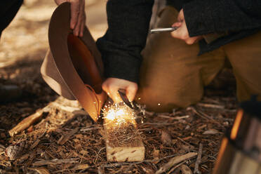 Midsection of bushcrafters enlighten fire in forest - SASF00045