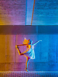 Woman dancing in multicolored light against wall - STSF02604
