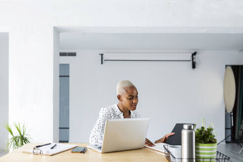 Kurzhaarige Frau arbeitet in einem hellen, modernen Büro - VABF03356