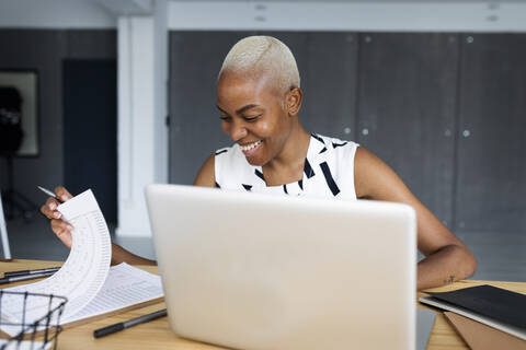 Lächelnde Geschäftsfrau, die in einem modernen Büro arbeitet und einen Laptop benutzt, lizenzfreies Stockfoto