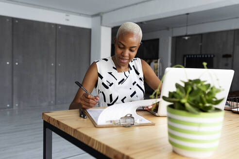 Businesswoman working in modern office, using laptop - VABF03369