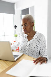 Geschäftsfrau, die in einem modernen Büro mit Laptop und Notizen arbeitet - VABF03381
