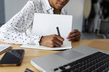 Businesswoman working in modern office with laptop using notes - VABF03382