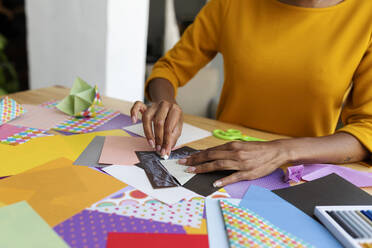 Origami-Künstlerin sitzt im Atelier und faltet buntes Papier - VABF03442