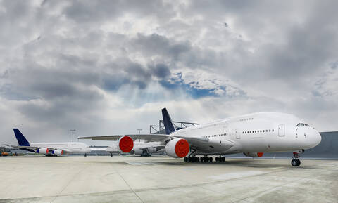 Airplane parked on apron under cloudy sky stock photo