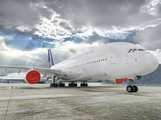 Auf der Startbahn eines Flughafens geparkter Airbus vor bewölktem Himmel - WEF00469