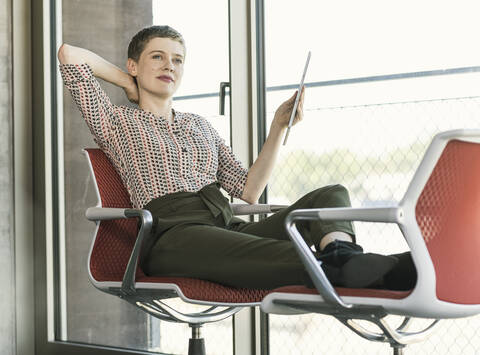 Relaxed businesswoman holding tablet in office stock photo