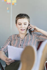 Businesswoman sitting on office chair talking on the phone - UUF21087